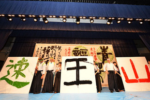 県立与野高校の書道部の手ほどきで選手が書道を体験。袴とハチマキ姿で獲得した賞を表す文字を表現。