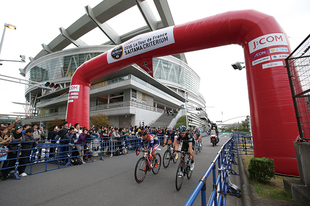 さいたまスーパーアリーナを背景に残り「1km」を示すフラムルージュを通る選手達